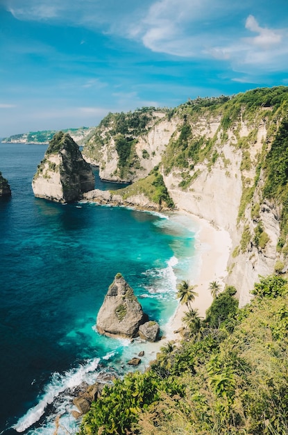 Playa de arena con montañas rocosas y agua clara en Diamond Beach Bali Indonesia