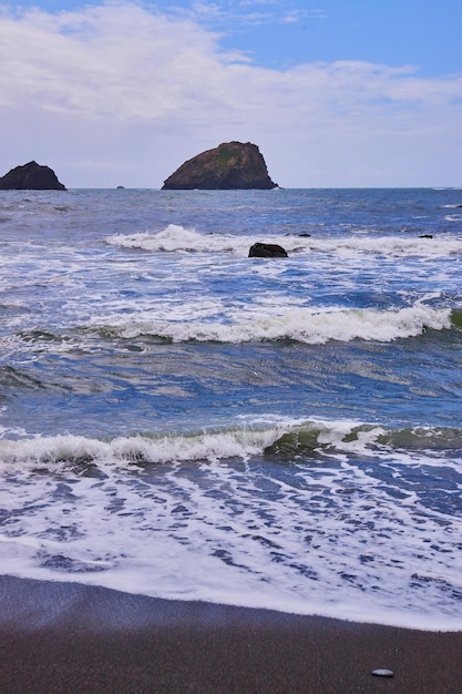 Playa de arena negra de la costa oeste con pequeñas olas rompiendo