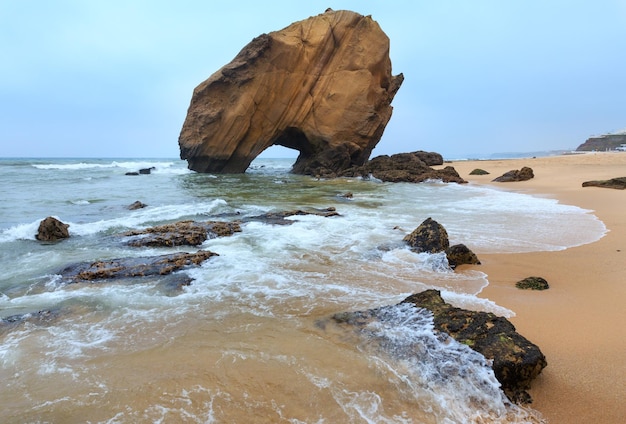 Playa de arena Praia de Santa Cruz con formación rocosa Portugal Misty weather