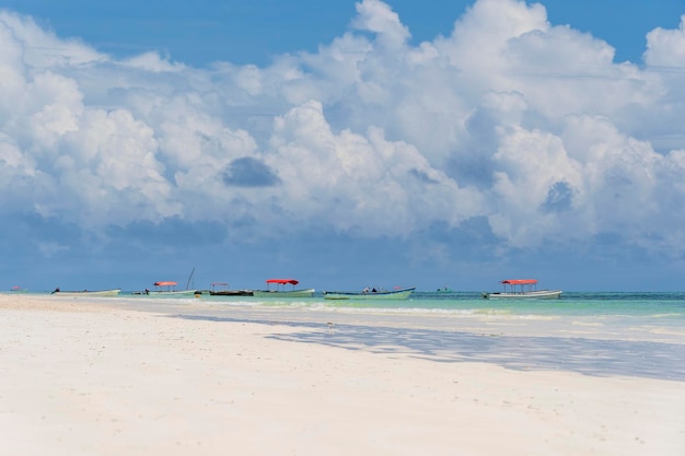 Playa de arena tropical, agua de mar clara y cielo azul con nubes blancas en la isla de Zanzíbar, Tanzania, África