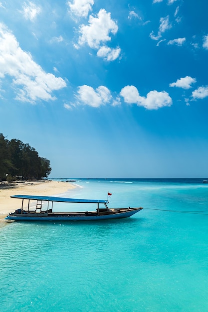 Playa de arena tropical con océano turquesa y barcos en las islas gili en lombok, indonesia