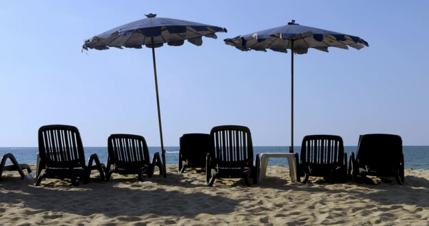 Playa de arena con tumbonas sombrillas.