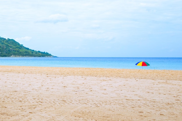 Playa de arena vacía con sombrilla brillante y montaña Viajes y turismo