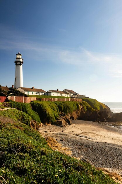 una playa con casas en el lado y un faro a la derecha