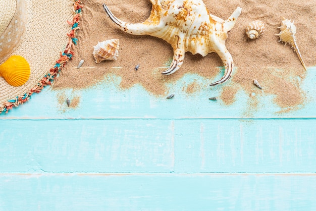 Playa y cáscaras del sombrero en el fondo de madera azul para el concepto del verano.