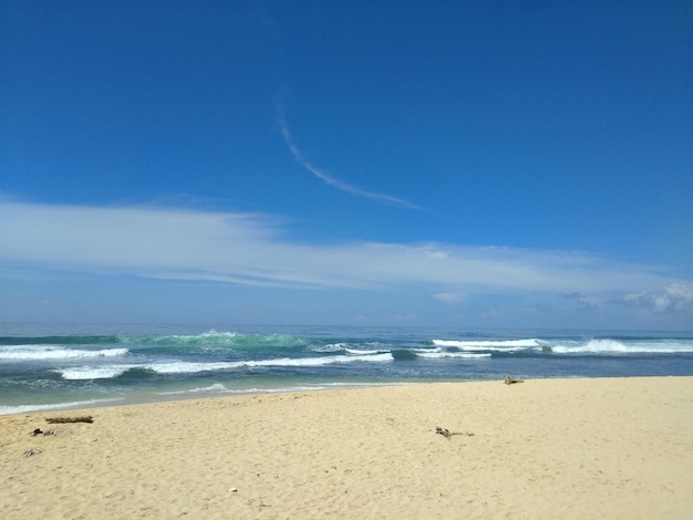 Una playa con un cielo azul y algunas nubes.