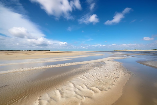 Una playa con un cielo azul y nubes al fondo.