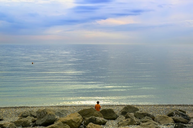 Una playa en la costa del Mar Negro Un hombre entre rocas mira el mar Adler Sochi Rusia 2021