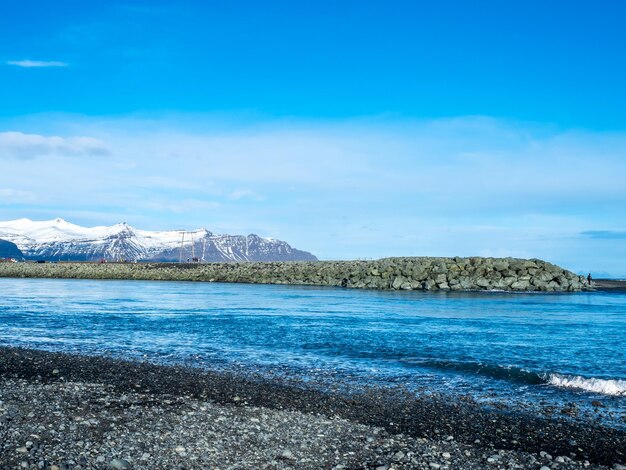 Playa de diamantes de arena negra con olas y montañas nevadas en Islandia