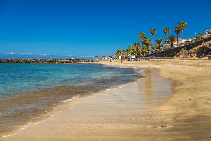 La playa del Duque, en Tenerife, presenta una escena serena con arenas suaves y aguas azules brillantes