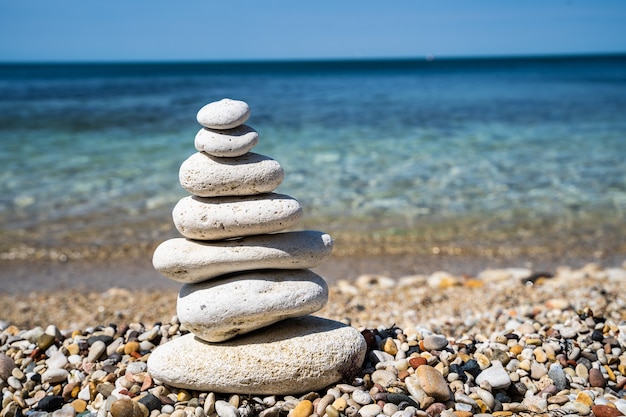 Playa de guijarros con primer plano de pirámide de piedra de equilibrio. Concepto de calma y equilibrio. Fondo borroso.