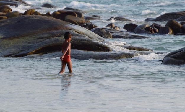 En la playa hay niños jugando alegremente en el mar. En vacaciones, a la gente le gusta relajarse en la playa. Capturado el 18 de abril de 2023 en la playa de Mae Ramphueng, Rayong, Tailandia.