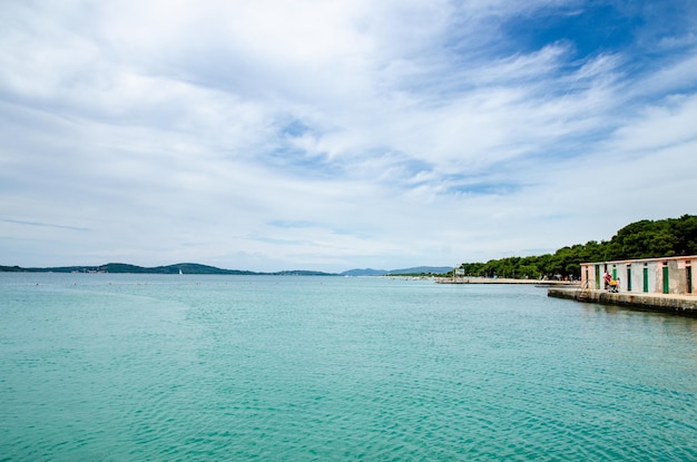 Foto playa de jadrija vista en la orilla de la gente nadando día de verano nublado lugar turístico para visitar