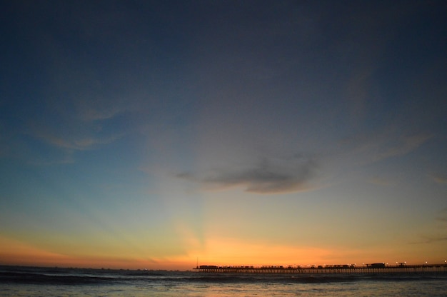 Playa con mar y muelle y gente.