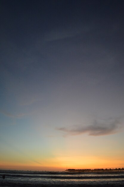 Playa con mar y muelle y gente.