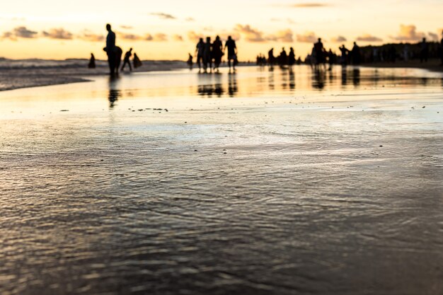 Playa de mar en la noche con personas de sombra desenfocadas con enfoque superficial