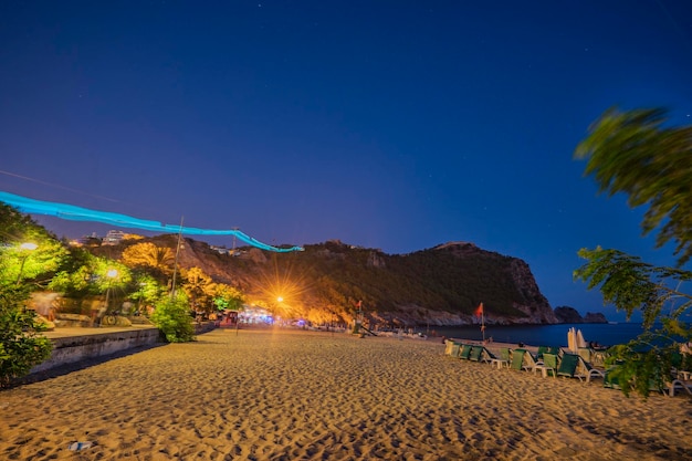 Una playa de noche con un faro en el lado izquierdo.