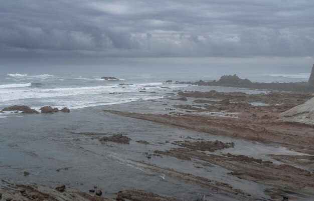 PLAYA NORTE CON OLAS Y ROCAS BAJO CIELOS NUBLADOS DE PRIMAVERA