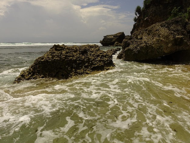 Una playa con olas rompiendo en las rocas