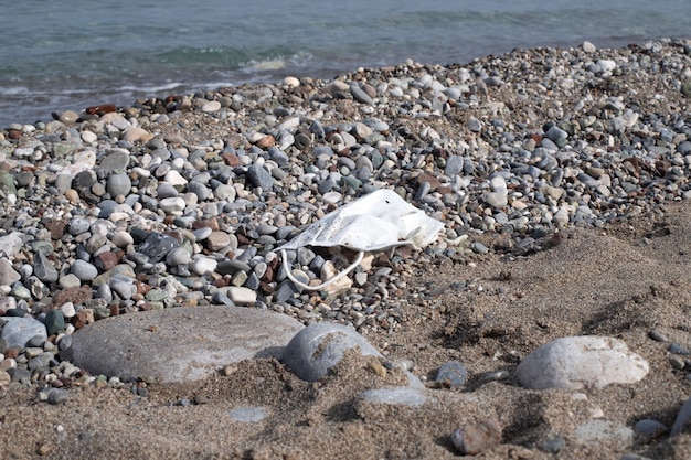Playa en la playa mediterránea con basura en forma de mascarilla médica. Desperdicio