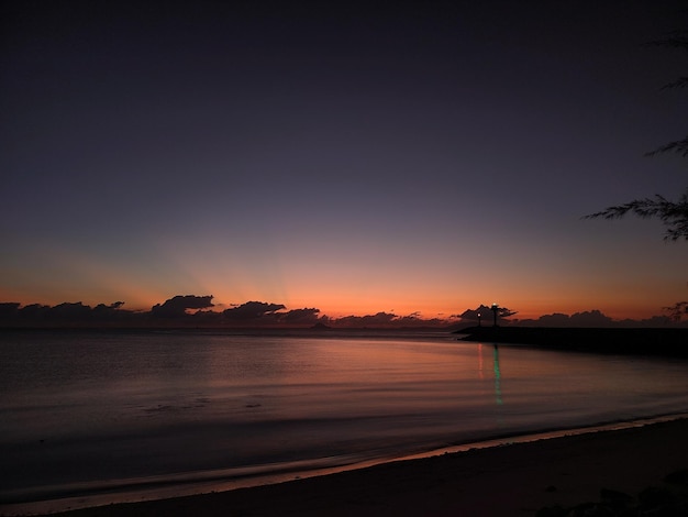 Una playa con puesta de sol y luz verde en el agua