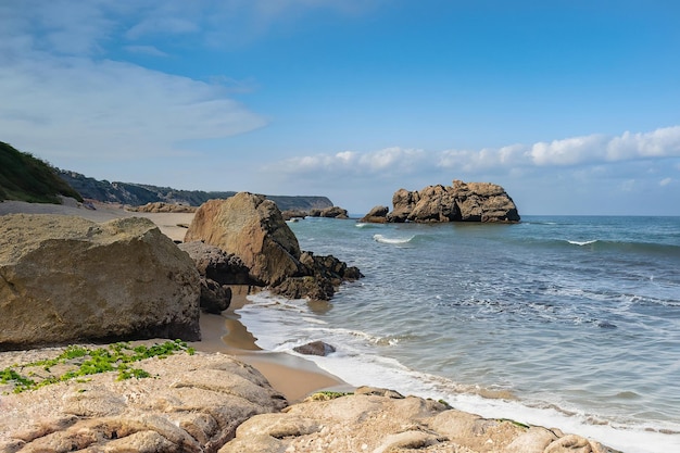 Una playa con rocas y un cielo azul.