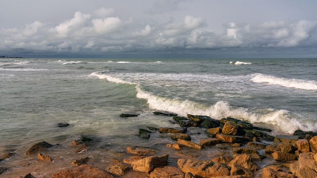 Playa rocosa vacía y mar tempestuoso en tiempo nublado