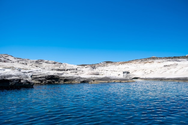 Foto playa sarakiniko en la isla de milos cyclades grecia formaciones rocosas blancas acantilados y cuevas sobre el mar azul