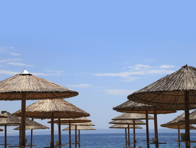 Playa soleada con sombrillas de mimbre y cielo azul