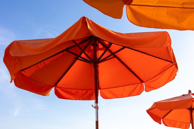 Playa de sombrilla naranja vivo con cielo azul brillante.