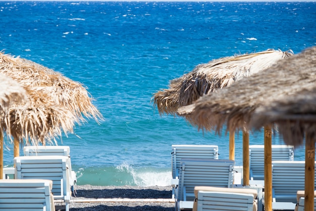 Foto playa con sombrillas y tumbonas junto al mar en santorini