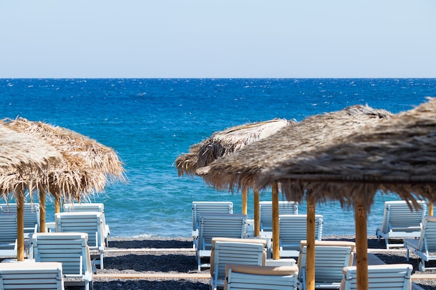 Playa con sombrillas y tumbonas junto al mar en Santorini