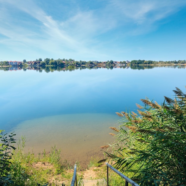 Playa tranquila del lago de verano con pendientes de madera hasta el agua