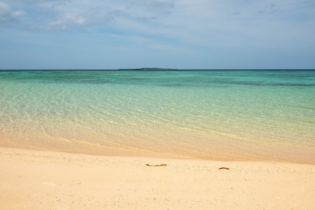 Playa tranquila con mar de superficie ondulada en calma, arenas suaves, isla al fondo. Isla de Iriomote.