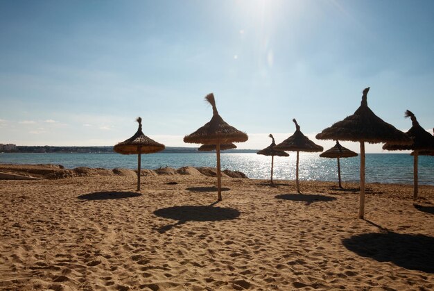 Playa vacía con sombrillas de paja, Mallorca, Islas Baleares, España