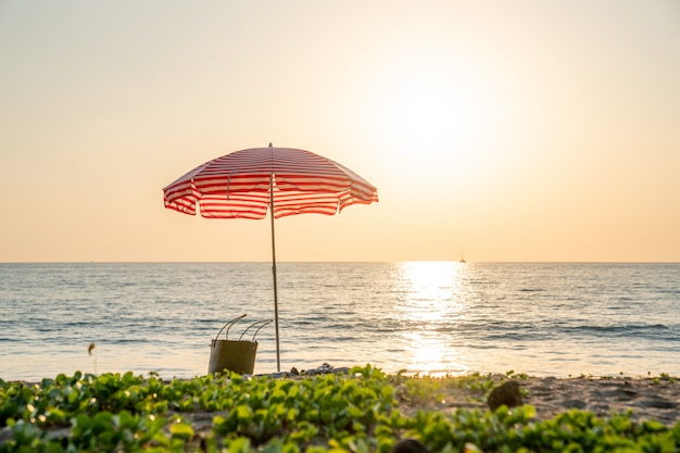 Playa de verano y sombrilla roja por concepto de vacaciones