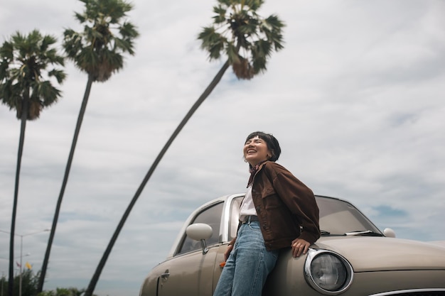 Playa de viaje de mujer asiática con coche clásico