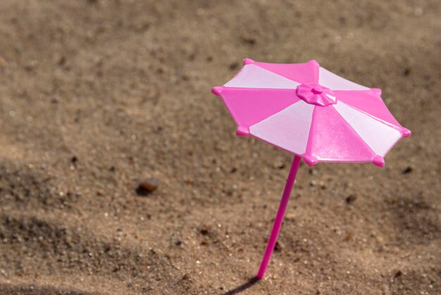 Playground caixa de areia infantil guarda-chuva de brinquedo nas cores rosa e branco em uma praia de areia à beira-mar psicodélico infantil foco seletivo