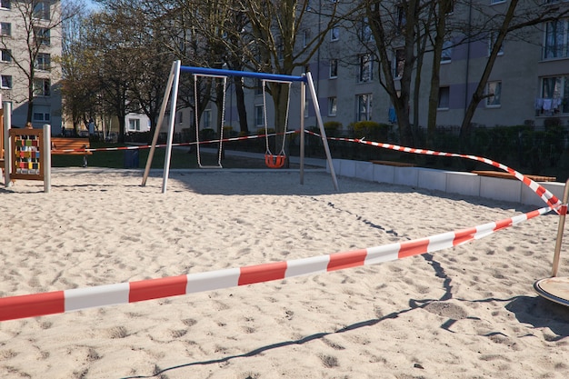 Playground vazio sem filhos, ligado a crianças e pais. fechado com fita de barreira branca vermelha listrada. restrições, quarentena para doenças causadas pelo novo coronavirus covid-19.