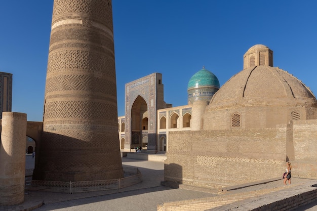 Plaza PoiKalyan con minarete Kalyan y antigua madraza con cúpula azul Bukhara Uzbekistán