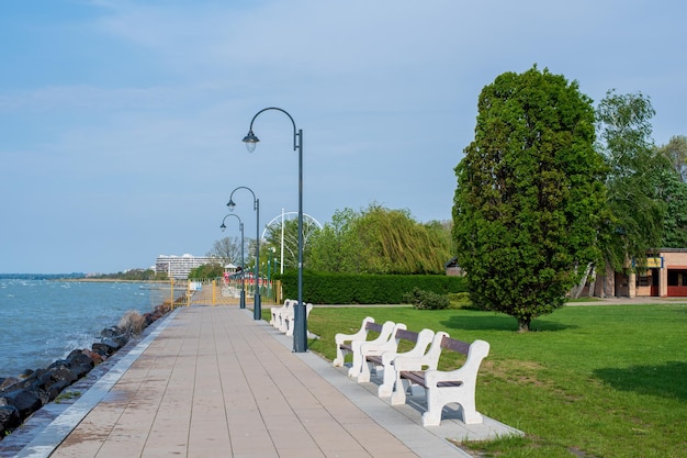 Una plaza principal verde a orillas del lago Balaton con árboles, bancos y flores.