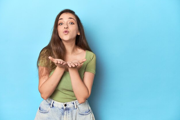 Plegando los labios y sosteniendo las palmas para enviar un beso en el aire