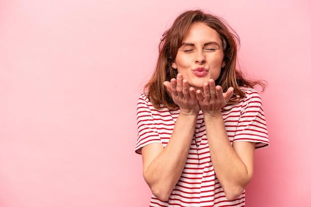 Plegando los labios y sosteniendo las palmas para enviar un beso al aire.