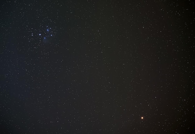 Plêiades (também conhecidas como Sete Irmãs) aglomerado estelar aberto no céu noturno de inverno, planeta vermelho brilhante Marte no canto inferior direito, foto de longa exposição