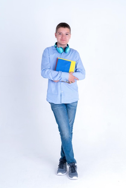 En pleno crecimiento, un adolescente caucásico con una camisa azul sosteniendo libros de maquetas Foto vertical