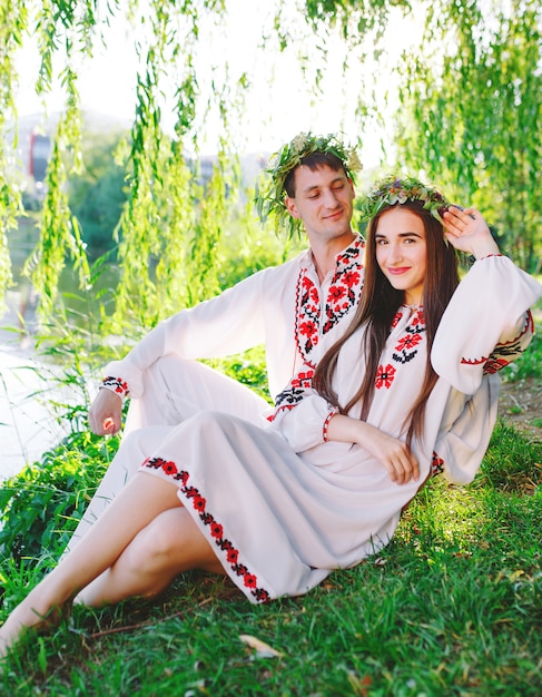 Pleno verano. Joven pareja amorosa en trajes eslavos en la orilla del lago. Fiesta eslava de Ivan Kupala.