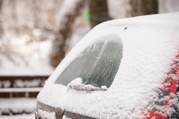 Foto plötzlich fiel schnee auf autos und straßen. ein autowischer reinigt die heckscheibe von einer dicken schneeschicht