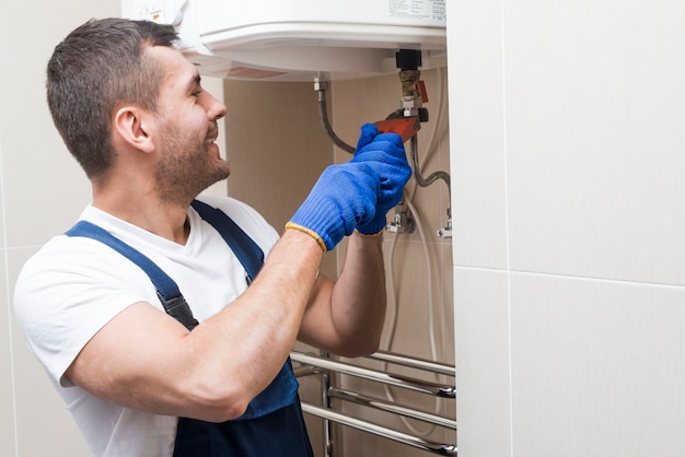 Foto plomero alegre que trabaja en baño