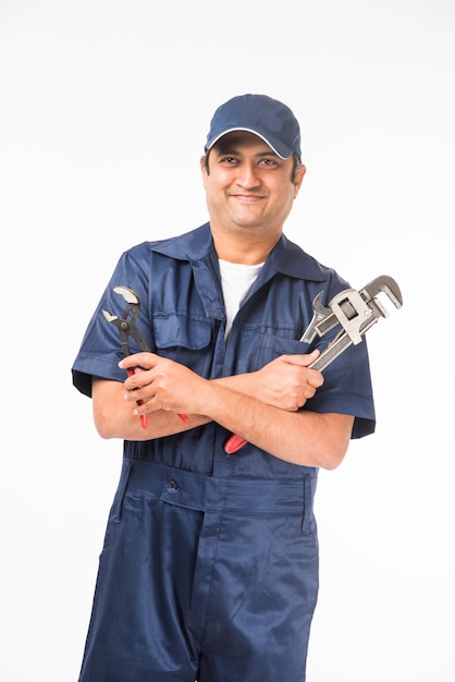 Foto plomero indio sonriente con llave de tubo o llave de plomería, vistiendo uniforme azul con tapa mostrando los pulgares hacia arriba. aislado