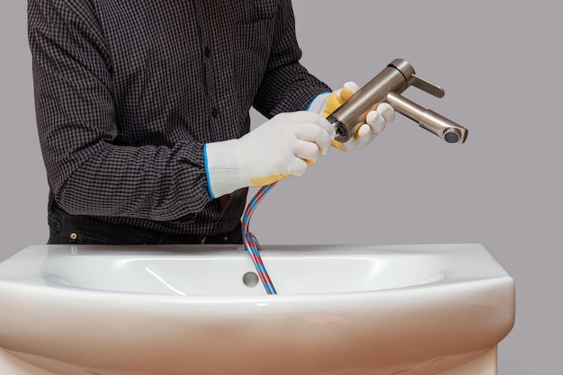 Un plomero instala un grifo en un baño y conecta una manguera al primer plano del grifo